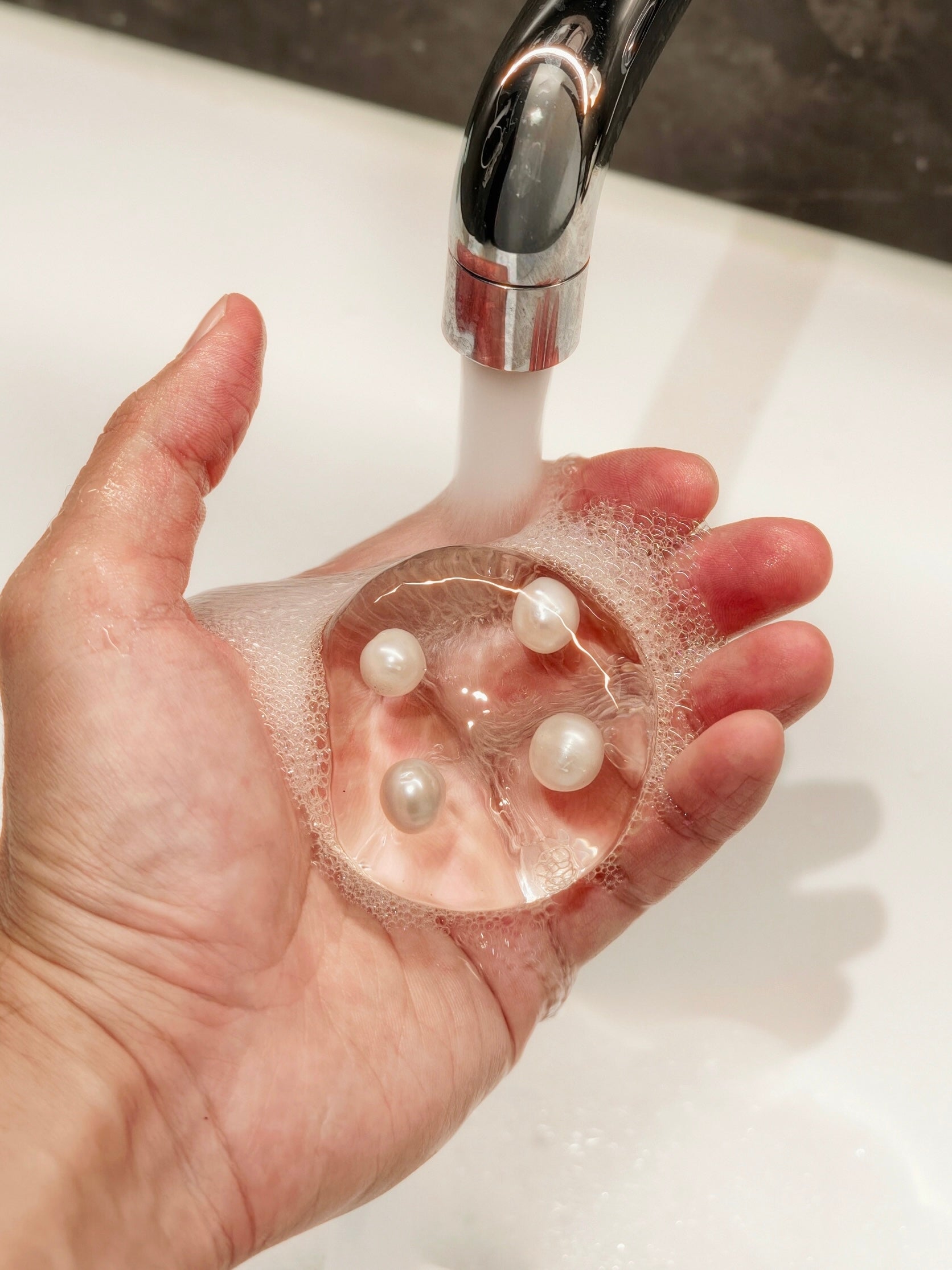 Transparent hydrating handmade soap with four genuine freshwater pearls creating a soft creamy lather under running water.